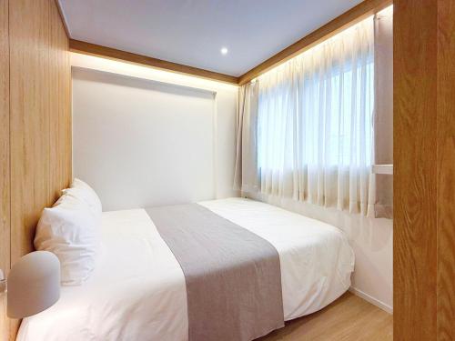 a bedroom with a white bed and a window at Euljiro Central 3BR Stay in Seoul