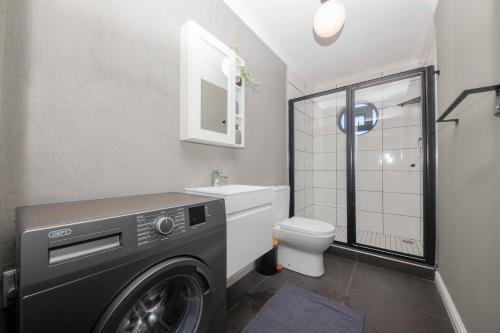 a washing machine in a bathroom with a toilet at Cape on Porterfield in Cape Town