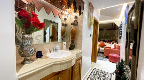 a bathroom with a sink and a vase with red roses at Appartements Luxe Simo in Fez