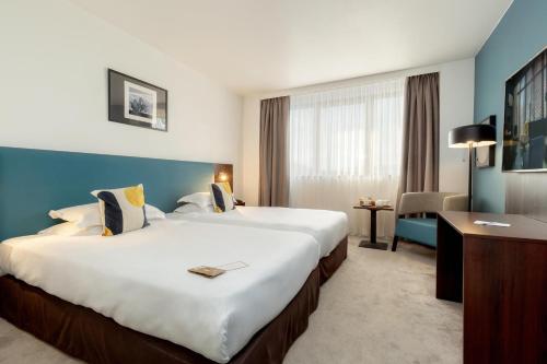 a hotel room with two beds and a desk at Best Western Hotel le Galice Aix-en-Provence in Aix-en-Provence