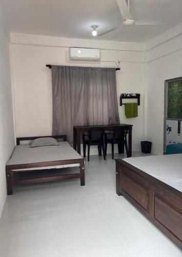 a bedroom with two beds and a table in it at Mapa Group Rest House in Kurunegala