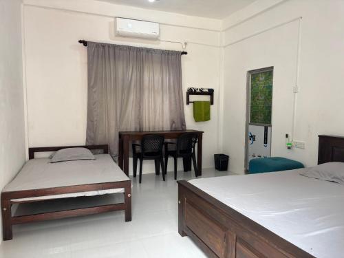 a bedroom with two beds and a desk and a table at Mapa Group Rest House in Kurunegala