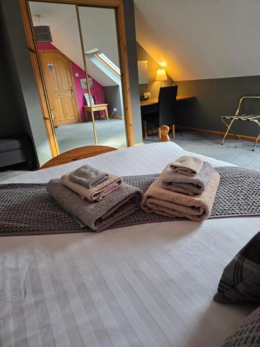 a bed with towels on it with a mirror at Corrie View in Invergarry