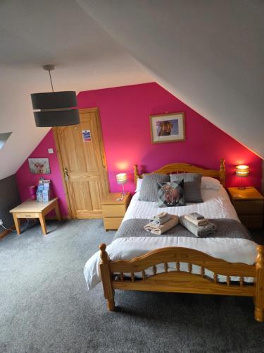 a bedroom with a large bed with a pink wall at Corrie View in Invergarry
