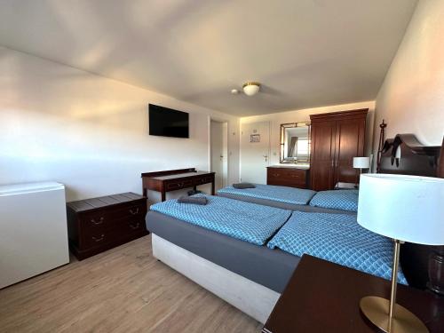 a bedroom with two beds and a desk and a television at Gästehaus am Harz in Goslar
