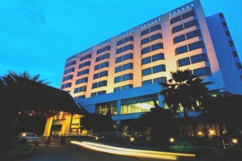 a large building with a palm tree in front of it at Laithong Hotel Ubon Ratchathani in Ubon Ratchathani