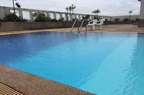 a blue swimming pool with two white chairs next to it at Laithong Hotel Ubon Ratchathani in Ubon Ratchathani