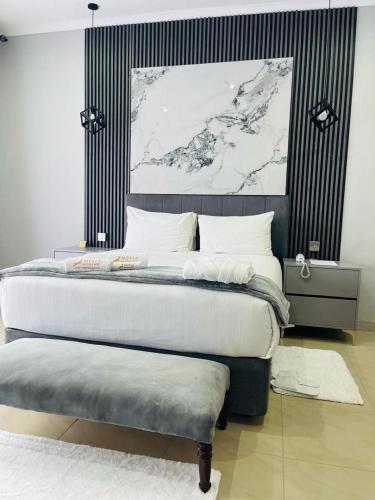 a bedroom with a large bed with a bench next to it at Mpala Boutique Hotel in Bulawayo