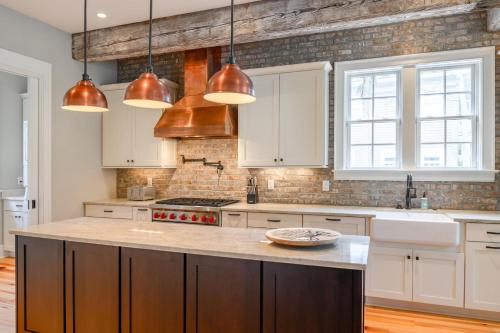 a kitchen with white cabinets and copper pendant lights at 233 Glen Abbey in Kiawah Island