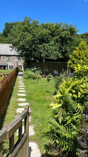 a garden with a wooden fence and green grass at River cottage Dartmoor in Holne