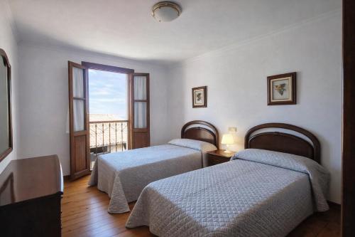 two beds in a hotel room with a balcony at Llanes Casa con Terraza y Barbacoa – La Jorcada in Porrúa