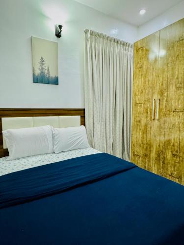 a bedroom with a blue bed and a window at Polo Apartments Lekki in Lekki