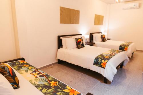 two beds in a room with two beds sidx sidx sidx at Hotel Plaza Los Tucanes in Santiago