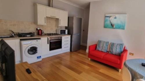 a kitchen with a red chair and a washing machine at Sandown Seaside apartment First Floor Kasala in Sandown