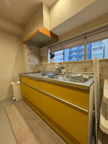 a yellow kitchen with a sink and a window at Hotel Sakura Riverside in Nagoya