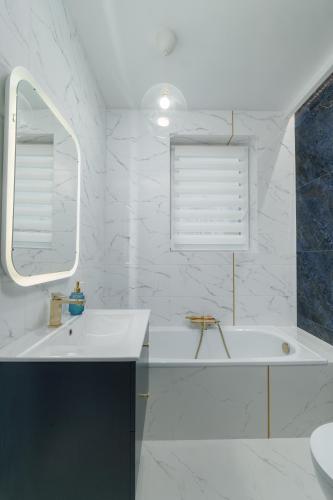 a white bathroom with a tub and a sink at Cozy Attic in Marki