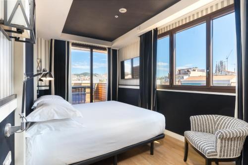 a bedroom with a bed and a chair and windows at Europark in Barcelona