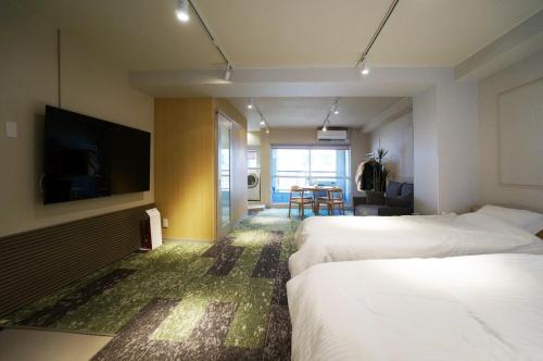 a hotel room with two beds and a flat screen tv at Hotel Sakura Riverside in Nagoya
