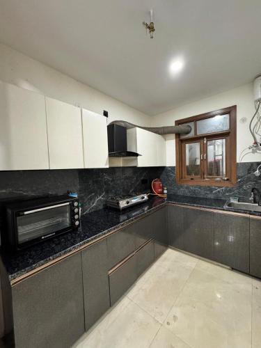 a kitchen with white cabinets and a microwave at 3BHK Independent Floor in New Delhi