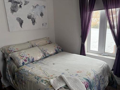 a small bed in a bedroom with a window at Gite La Ptite Falaise hébergement touristique et appartement in Sainte-Anne-des-Monts