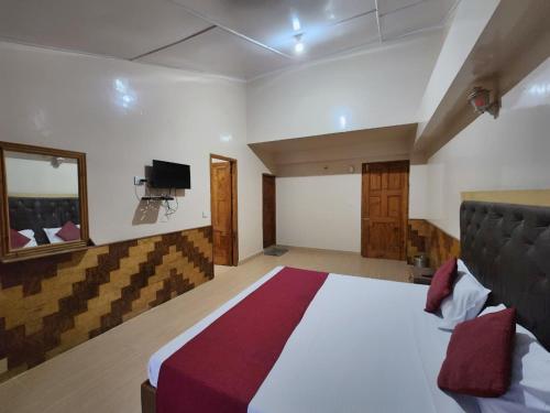 a bedroom with a large bed and a tv at Hotel tridev in Manāli