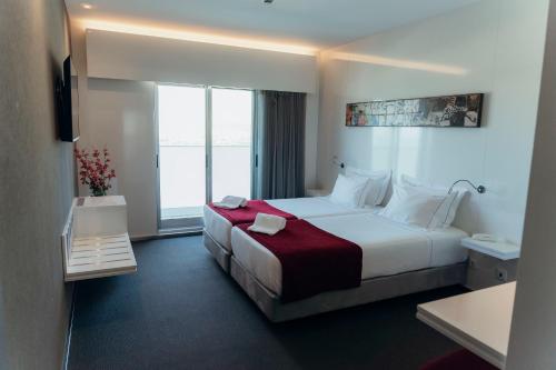 a hotel room with a bed and a large window at Hotel Costa Verde in Póvoa de Varzim