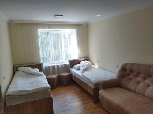 a room with two beds and a couch and a window at Vadamar Apartment in Sisian