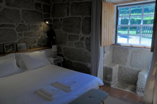 a bedroom with a white bed with a stone wall at Quinta do Caritel in Vouzela