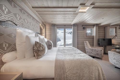 a bedroom with a large bed with pillows and a television at Hotel Le K2 Altitude in Courchevel