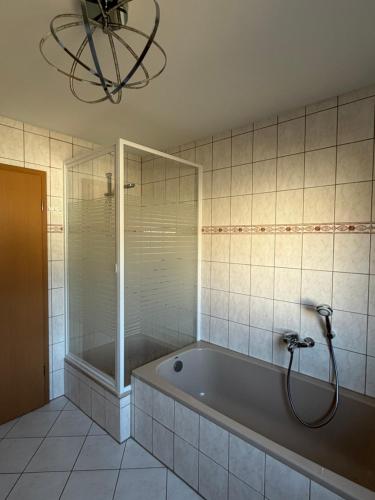 a bathroom with a tub and a shower and a chandelier at Ferienwohnung in Staufenberg- Treis in Staufenberg