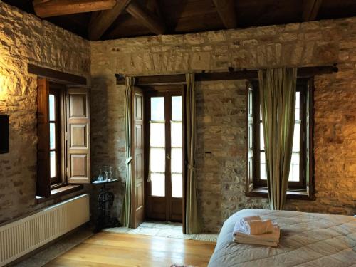 a bedroom with stone walls and a bed with windows at Old Inn in Karpenision