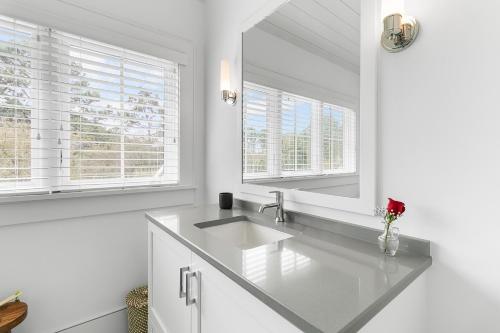 a white bathroom with a sink and two windows at 117 Halona in Kiawah Island