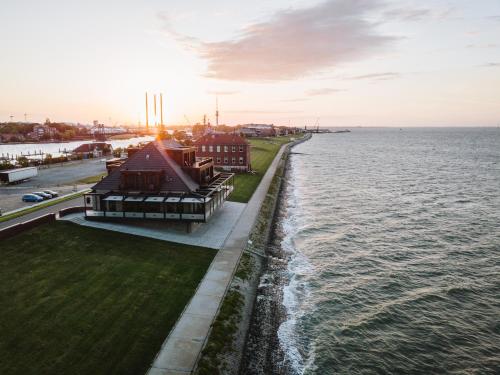 a building on the shore of the water with the sunset at Fliegerdeich Hotel & Restaurant in Wilhelmshaven