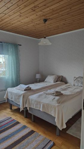 two beds in a bedroom with a wooden ceiling at Mumrila in Pori
