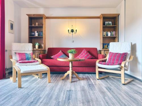 a living room with a red couch and two chairs at Sonnenhof Seeg 08 in Seeg