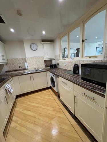 a kitchen with white cabinets and a wooden floor at Dock View Lodge in Liverpool
