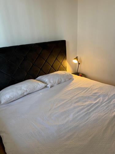 a bedroom with a large white bed with a black headboard at Apartman Galah in Vukovar