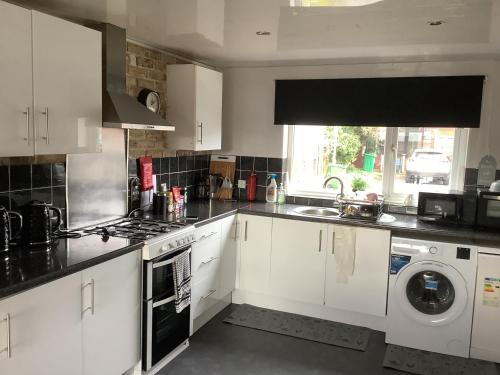 a kitchen with white cabinets and a washer and dryer at 5 BedRm Hse! Ev! & Nr CityCentre! in Manchester