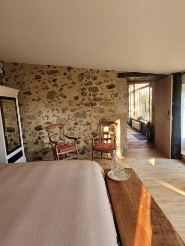 a room with two chairs and a stone wall at Aumônerie du Prieuré in Pouzauges