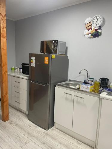 a kitchen with a stainless steel refrigerator and a microwave at departamento central in Valdivia