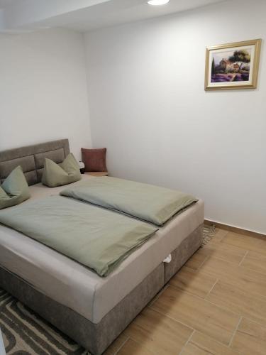 a bed in a room with a white wall at Apartman Antonio 2 in Karlovac