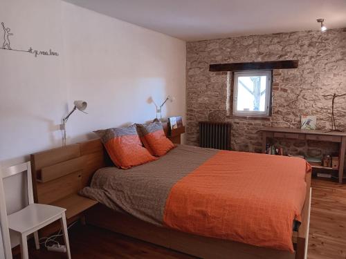 a bedroom with a bed with orange sheets and a window at Escale Zen en Quercy in Montalzat