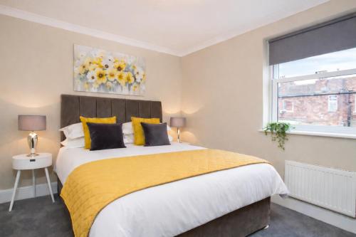 a bedroom with a large bed with a yellow blanket at Knavesmire Mews 3 bedrooms-Free parking in York