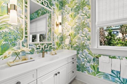 a bathroom with a white sink and a tropical wallpaper at 38 Surfsong in Kiawah Island