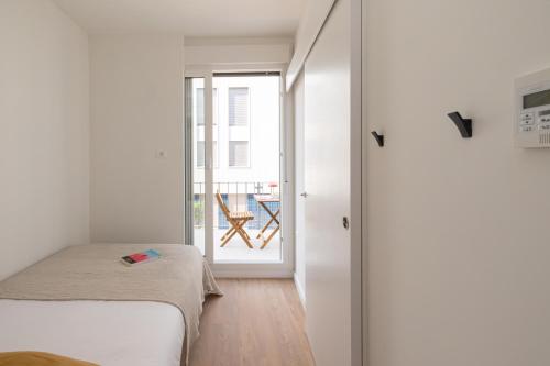 a bedroom with a bed and a door to a balcony at Canvas Valencia Burjassot in Burjassot