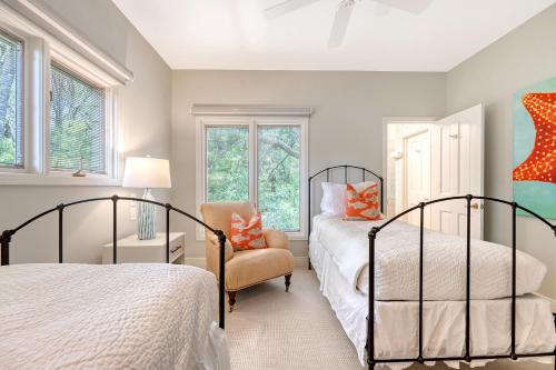 a bedroom with two beds and a chair and windows at 338 Surfsong in Kiawah Island