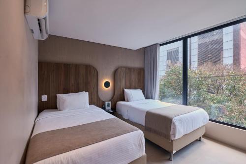 a hotel room with two beds and a window at Hotel Lincoln in Medellín