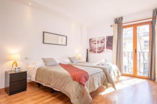 a bedroom with two beds and a large window at Residencial Suites Valldemossa - Turismo de Interior in Valldemossa