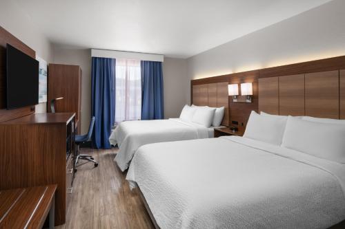 a hotel room with two beds and a flat screen tv at Garner Hotel Pigeon Forge Downtown by IHG in Pigeon Forge