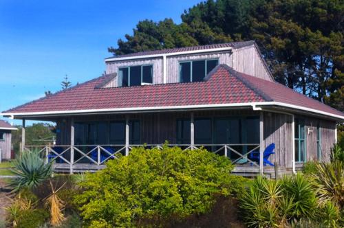 a house with a red roof with a blue bird standing in front at Thornton Beach Holiday park in Thornton